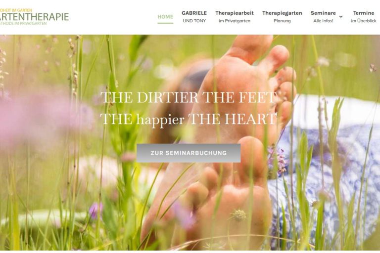 Nahaufnahme von nackten Füßen im Gras, mit dem Text „Je schmutziger die Füße, desto glücklicher das Herz“