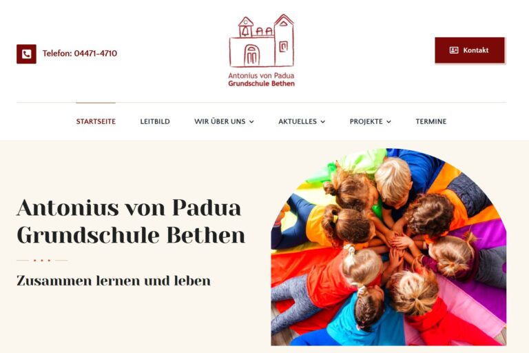 Website der Antonius von Padua Grundschule Bethen mit Logo und Foto von Kindern, die in einem Kreis liegen und Hände in der Mitte zusammenlegen.